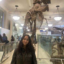 Brianna Moreira in front of a t-rex exhibit in a museum.